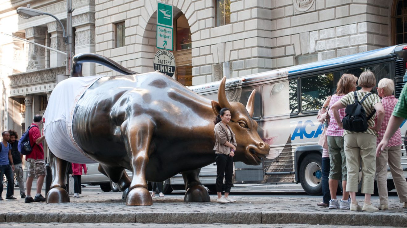 A photo of the Wall Street Bull in New Yorking wearing underwear while surrounded by a crowd.