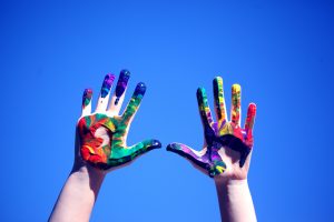 A photo of rainbow paint on hands to represent LGBT respondents of theinclusion survey