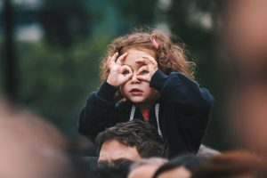 A photo of a young girl making circles over her eyes, representing binoculars