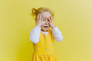 A photo of a young girl in a yellow dress on a yellow background