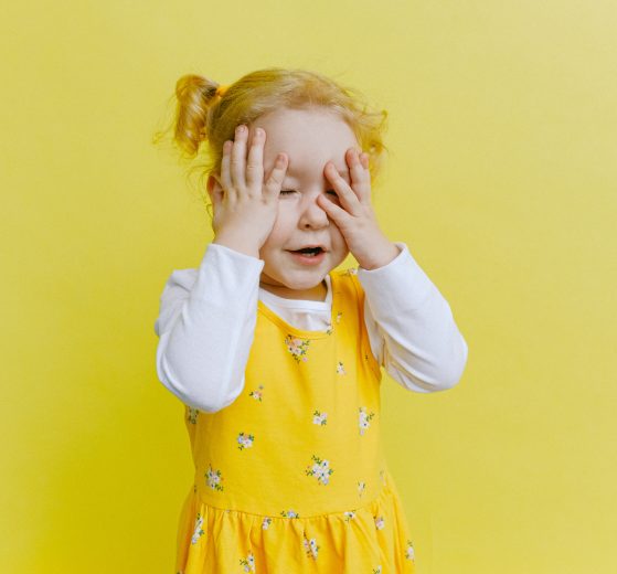 A photo of a young girl in a yellow dress on a yellow background