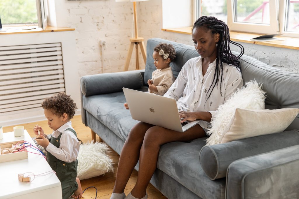A photo of a woman doing remote work with children in room
