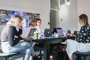 Three women on laptops sitting at a table in an office, representing women-founded startups