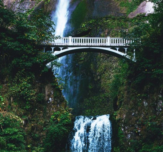 A bridge in the mountains above a waterfall, representing a bridging of the funding gap