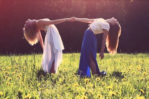 Two women bending backwards while holding hands in a meadow, representing brand partnerships
