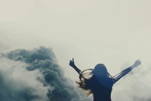 Woman with arms wide open to the clouds