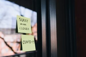 Sticky notes on a business's window saying it is closed due to COVID