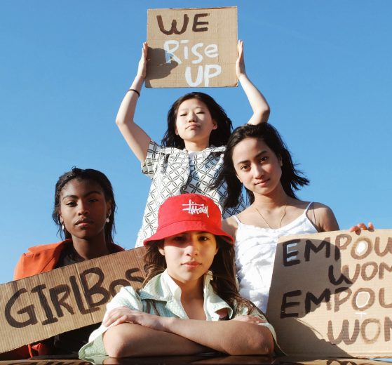 Four young women holding up women's empowerment signs
