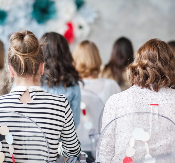 Back view of a group of women sitting at a conference, representing the Women's Venture Summit