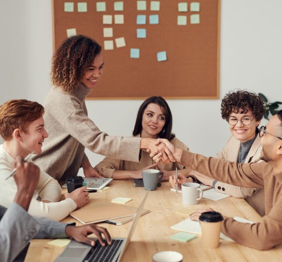 Three men and three women greeting each other at a boardroom table, representing gender parity in the boardroom