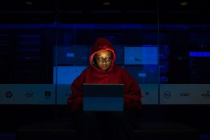 Woman in sweatshirt using laptop in front of screens