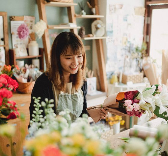 Female floral shop owner working among flowers, representing a women being helped by the Comcast RISE program