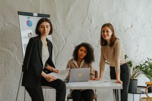 Three women around a white table in an office, representing women business owners