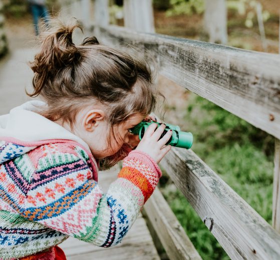 A photo of a young girl using binoculars, representing your business vision