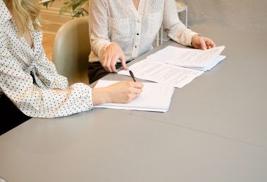 Two women sitting at table, poring over report representing HR Industry Trends Report