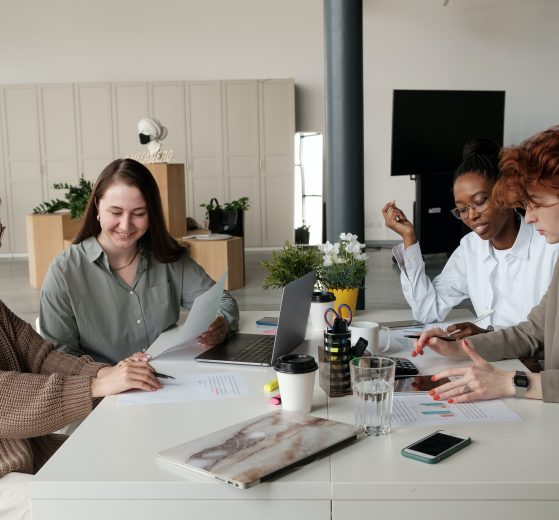 Four women working at a table together, representing The Trust and Luminary's exclusive partnership