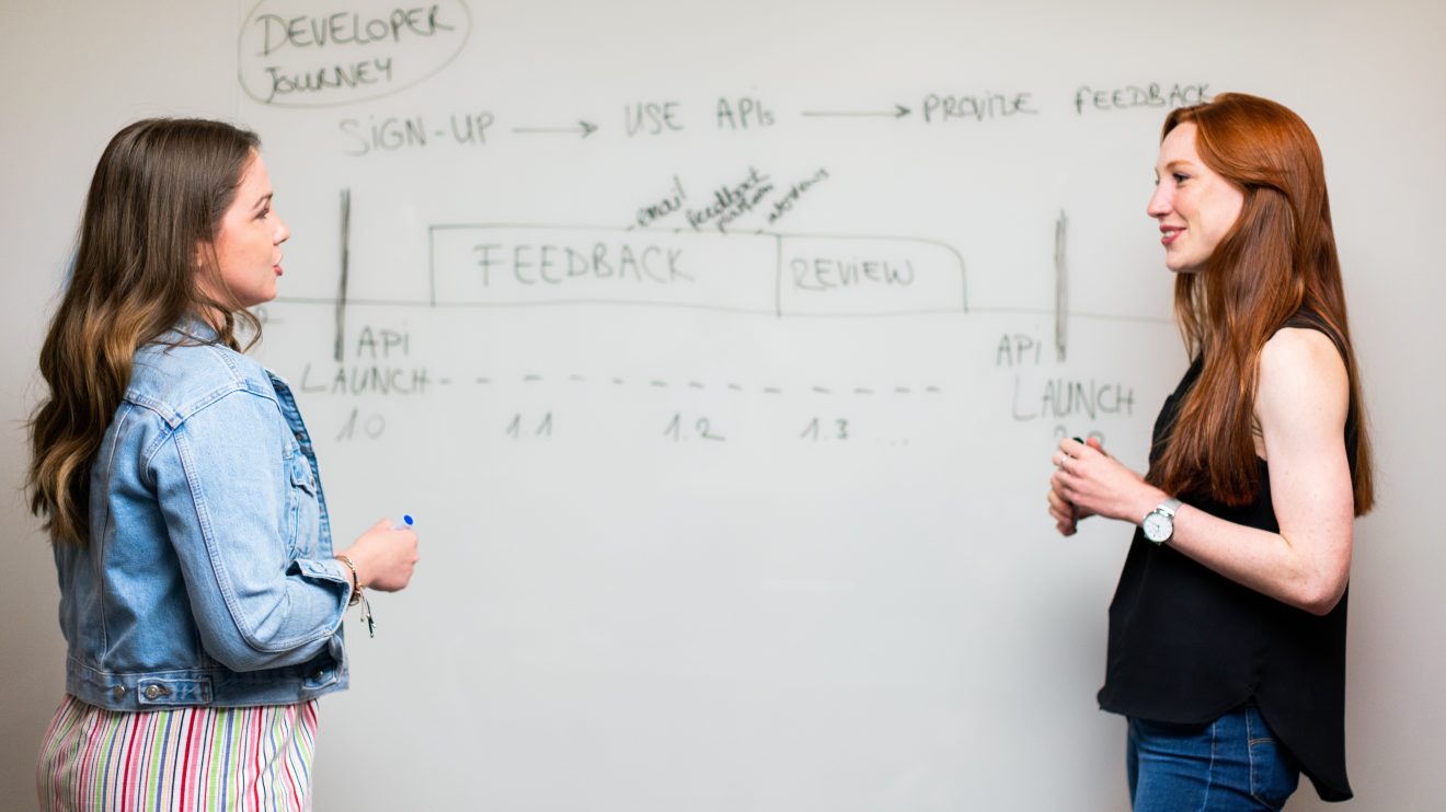 Two women brainstorming at a whiteboard, representing people pursuing entrepreneurship during The Great Resignation