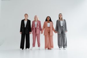 Four women holding hands against a white backdrop, representing female leaders