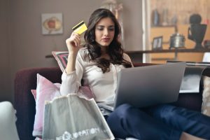 Woman holding credit card while shopping on laptop, representing Clearco and e-commerce