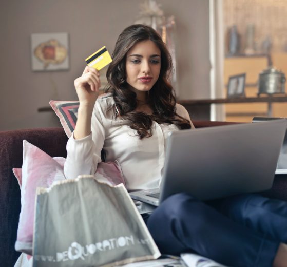Woman holding credit card while shopping on laptop, representing Clearco and e-commerce