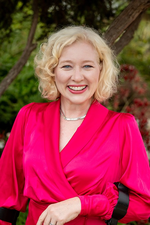 Amy Graves in a coral dress forward facing headshot